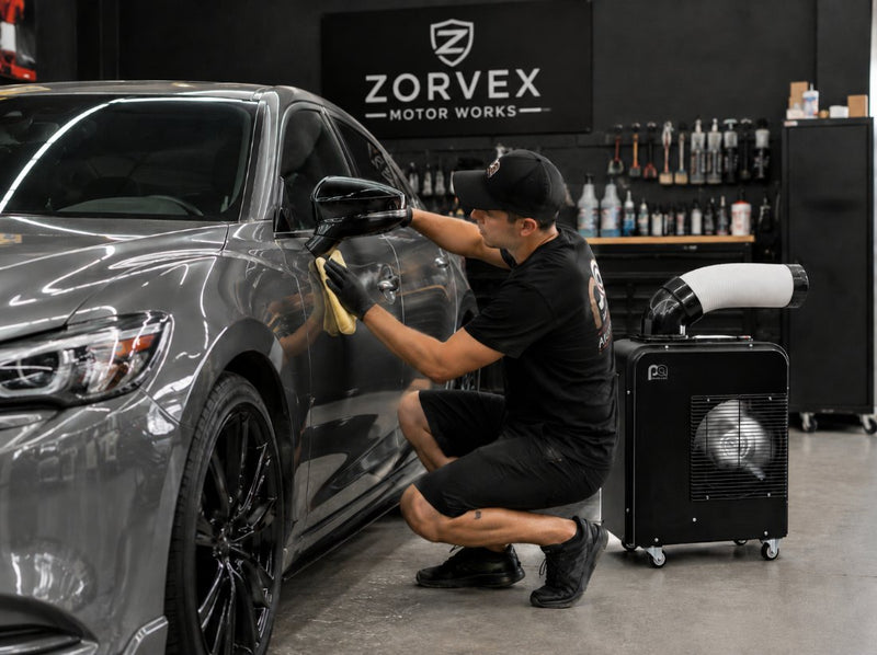 Auto detailer washing a car while The HVAC Spot blows cold air on them