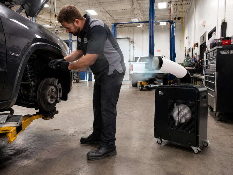 Mechanic working under a car on a 2-post lift with The HVAC Spot aimed at them